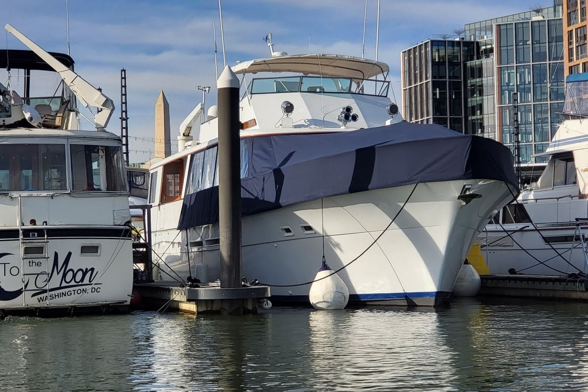White yacht with a dark canvas cover and side enclosure at the dock